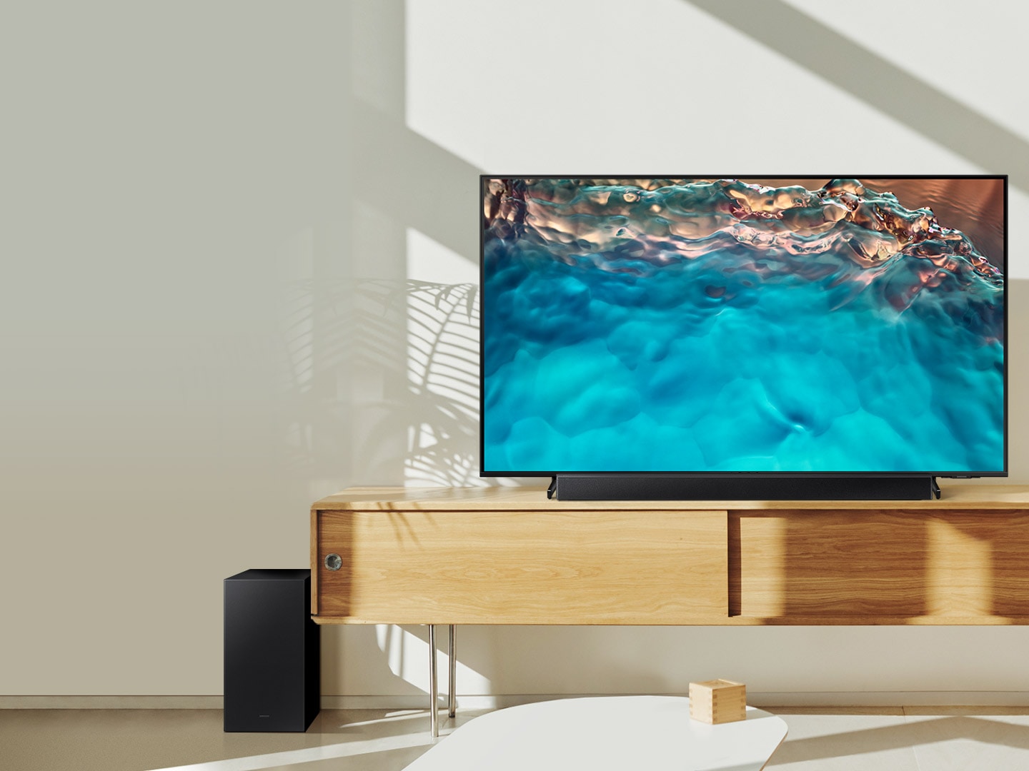 Soundbar dòng B và loa siêu trầm của Samsung được đặt cùng với TV Crystal UHD trên tủ phòng khách.